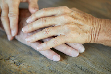 Senior couple hands consoling on wooden table
