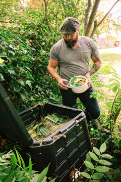 Mature man discarding kitchen scraps on compost pile