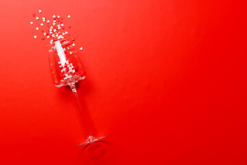 A champagne glass adorned with heart-shaped decor on a vibrant red background