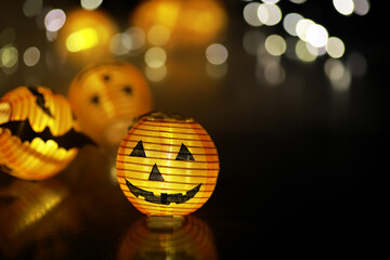 Obraz premium Glowing Halloween Jack-o'-Lantern Decorations with Bokeh Background Lights
