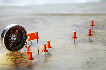 Compass and Red Push Pins on Map Indicating Navigation and Travel Planning