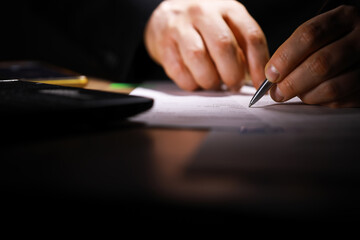 Business Professional Signing Document in Dimly Lit Office