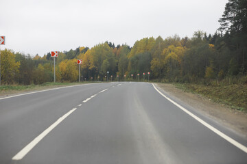 Empty Highway through Autumn Forest with Direction Signs