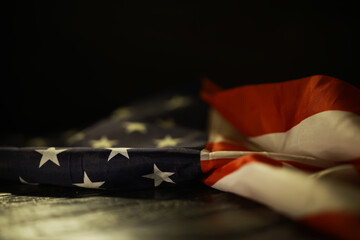 Close-up of Weathered American Flag Lying on Dark Surface with Dramatic Lighting