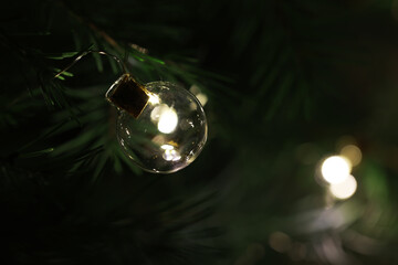 Golden Christmas Tree Ornament Glittering Among Green Pine Needles with Soft Bokeh Lights