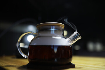 Glass Teapot with Steaming Tea on Wooden Table: Cozy and Warm Beverage Vibes