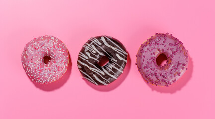 A colorful assortment of vibrant donuts with various toppings arranged on a pink