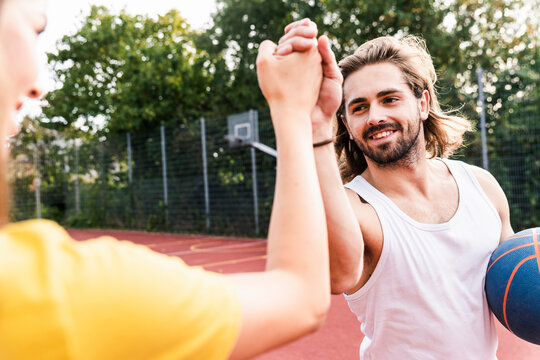 Young man and young woman high-fiving after basketball game