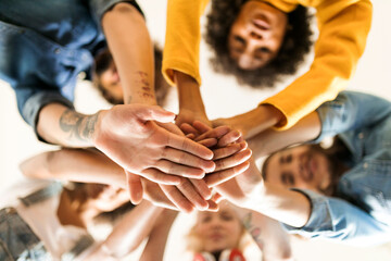 Group of happy friends huddling and stacking hands