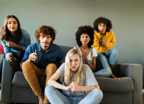 Nervous friends sitting on couch watching tv - Powered by Adobe