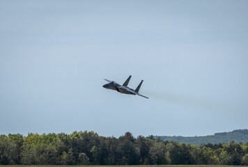 Fighter jet soaring over green forest