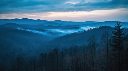 Obraz premium Blue mountain range at dusk with mist between the hills.