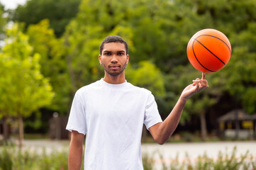 Young positive man holding a ball on the tip of his finger