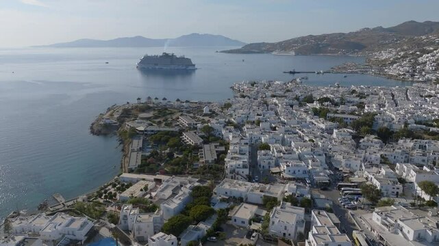 Mykonos town Fabrika aerial drone shot with a huge CruiseShip in the back at sunset and view of the whole town