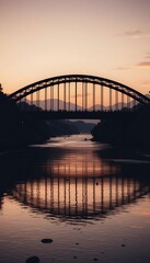 Fototapeta premium Silhouette of an arched bridge over a river at twilight