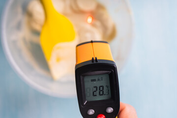 A pyrometer measures the temperature of white molten chocolate.