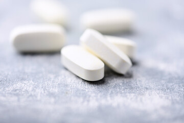 Arginine alpha-ketoglutarate (AAKG) tablets. Bodybuilding food supplements on wooden background. Soft focus. Close up. Copy space.