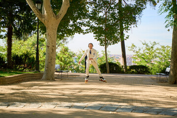 Man roller skating on a park pathway surrounded by trees and a city view