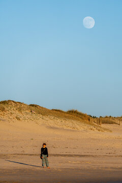 Woman standing on beach under moonlight in Vila do Conde