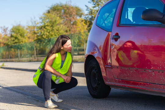Woman Assessing Damage on Red Car After Minor Traffic Collision