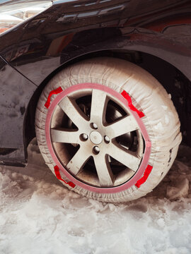 Snow-covered car tire with red snow chain