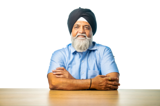 Senior Sikh man sitting at table with white background, expressing various emotions and gestures - Powered by Adobe