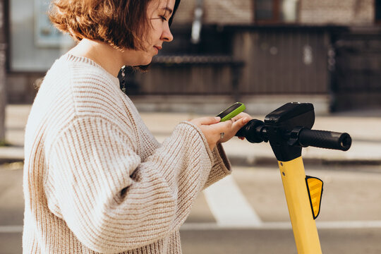 Woman uses smartphone to scan QR code on electric scooter