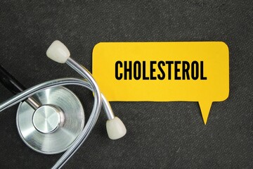 stethoscope and colored paper with the word cholesterol. a fatty substance that is part of the...