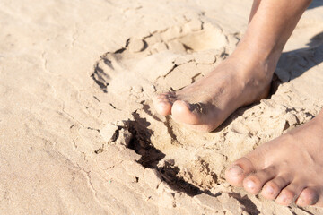Image of female feet on the golden sand of a beach. Concept: Vacation, sun and beach, summer season, sun cream, relax and wellness.