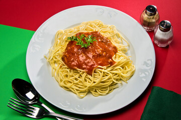 Plato de espaguetis con salsa de tomate y perejil en plato blanco.