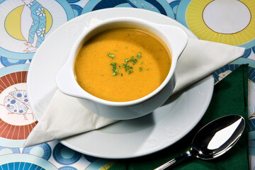 Sopa cremosa servida en bol blanco con decoración de perejil.