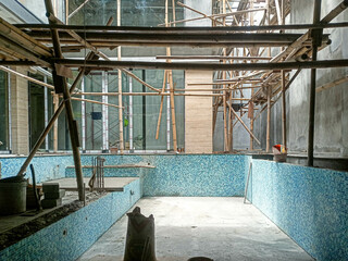 Obraz premium Workers are building a swimming pool in the middle of a building using bamboo scaffolding.