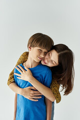 A young mother and her son share a tender hug, expressing warmth and love in a minimalistic studio.