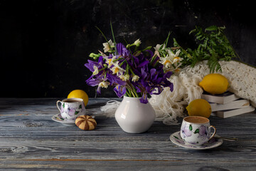 Still life with cups of coffee, field irises and daffodils and lemons close-up © TETYANA