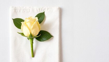Fototapeta premium Yellow rose boutonniere placed on white fabric for elegant wedding decor, wedding ceremony