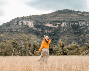mulher de saia longa e chapéu correndo com serra de santo antonio ao fundo em campo maior, piauí 
