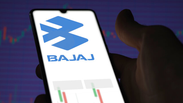 An investor analyzing the bajaj auto etf fund on a screen. A phone shows the prices of Bajaj Auto