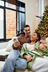 Fototapeta premium A couple shares quality time in their cozy, decorated apartment for Christmas.