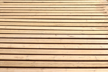 Obraz premium Wooden decking on the beach, close-up on the boards. Boardwalk. Background. Weathered wooden boards with scattered sand, summer warm lighting. Selective focus