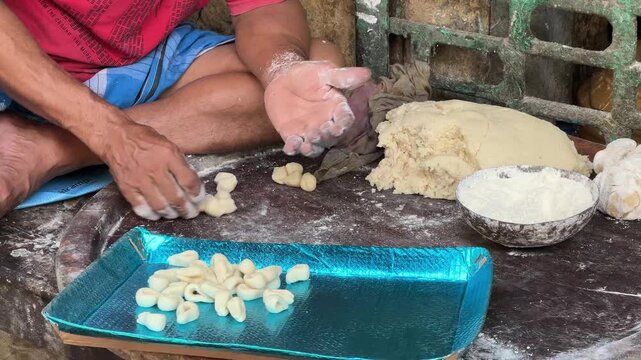 Camera shot of making traditional Bengali gujias by hand and placing each one on a tray of sweets.