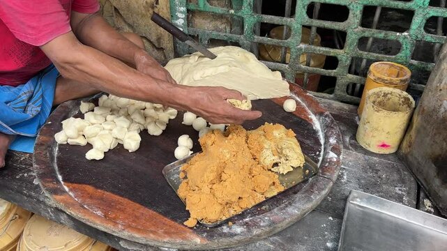 Bengali thakur or cook is filling puris with delicious fillings in a local sweet shop in Bengal, India.