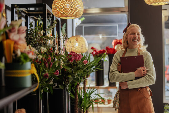 Cheerful florist holding a book in shop