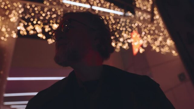 Smiling Mature man smiling while browsing photos on his smartphone. illuminated screen emphasizes the joy and ease of digital technology for reliving memories and sharing moments effortlessly
