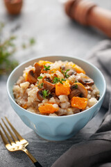 Pumpkin mushrooms risotto with fresh thyme in ceramic bowl. Italian Cuisine.