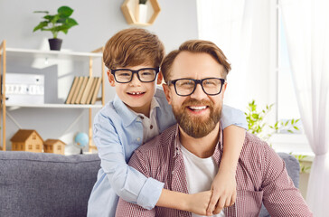 Positive portrait of a young happy Caucasian son embracing his delighted father at home, both...