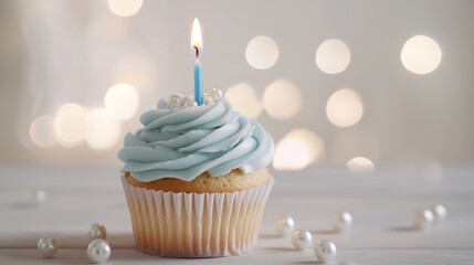 Elegant Blue Cupcake with Lit Candle and Pearl Decorations on Bokeh Background