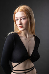 Portrait of a blonde woman with freckles in a sexy top and denim shorts in a studio.