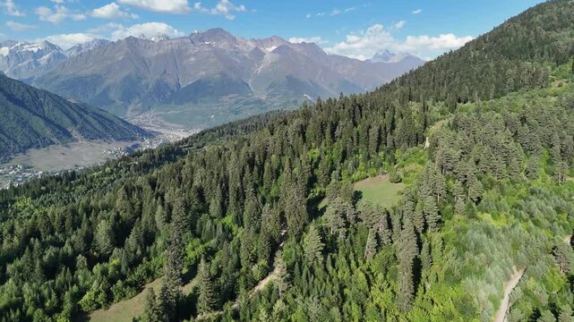 Aerial view of highland Mestia town, located in Majestic Caucasus Mountains with wooded hills, Ushba peaks and Chalaadi Glacier in Svaneti region, Georgia.