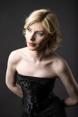 Fototapeta premium Expressive young blonde under a bob in the studio. In a black corset and dress.