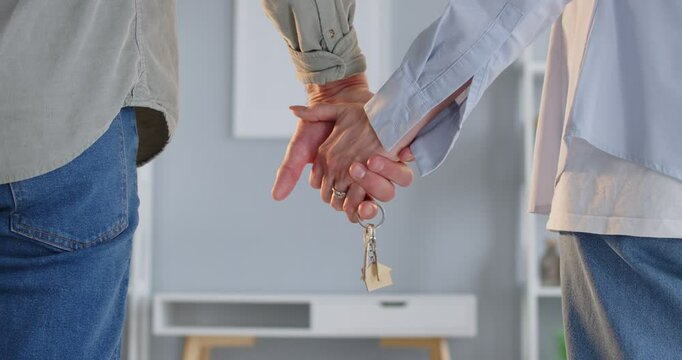 Young couple hand holding with key, welcome to new house, satisfied homeowners moving own flat, first real estate home and apartment, close up, purchase property deal, starting new life together 